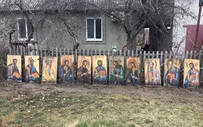 A row of paintings on the side of a fence.