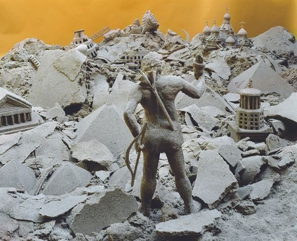 A statue of an archer in the middle of rubble.