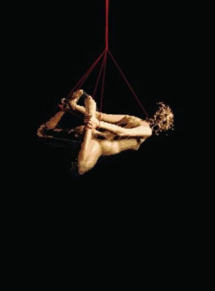 A man hanging from a rope in the dark.
