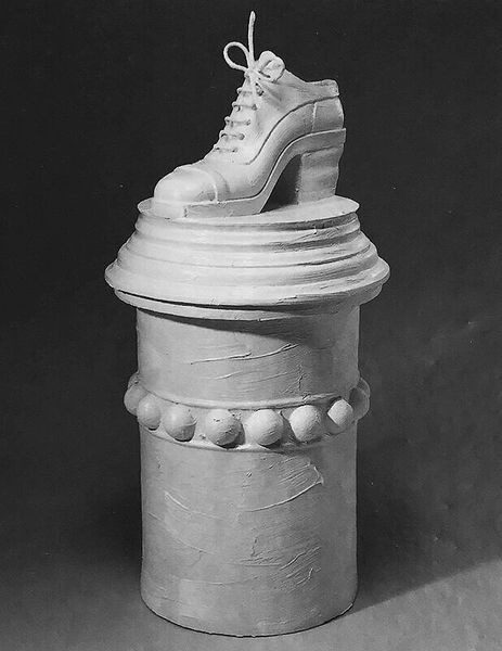 A statue of a shoe on top of a pillar.