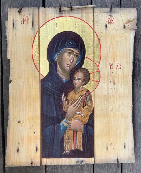 A painting of mary holding jesus on wood.