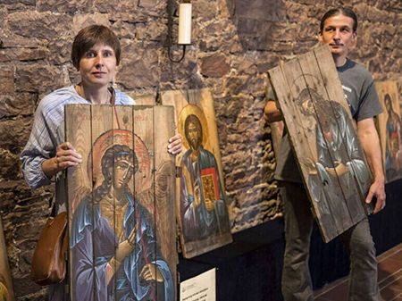 Two people holding up paintings of jesus and a woman.