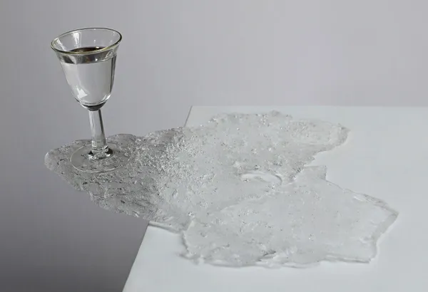 A glass of wine and some white substance on the table.