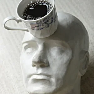 A cup of coffee is sitting on top of a head.
