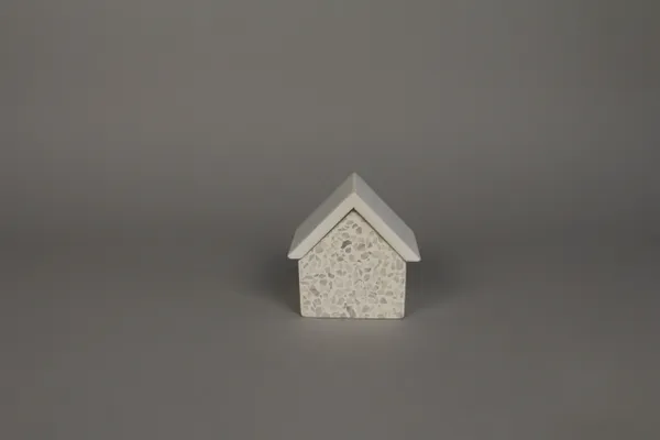 A small white house on top of a gray surface.