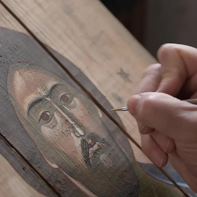 A person is painting on wood with a needle.